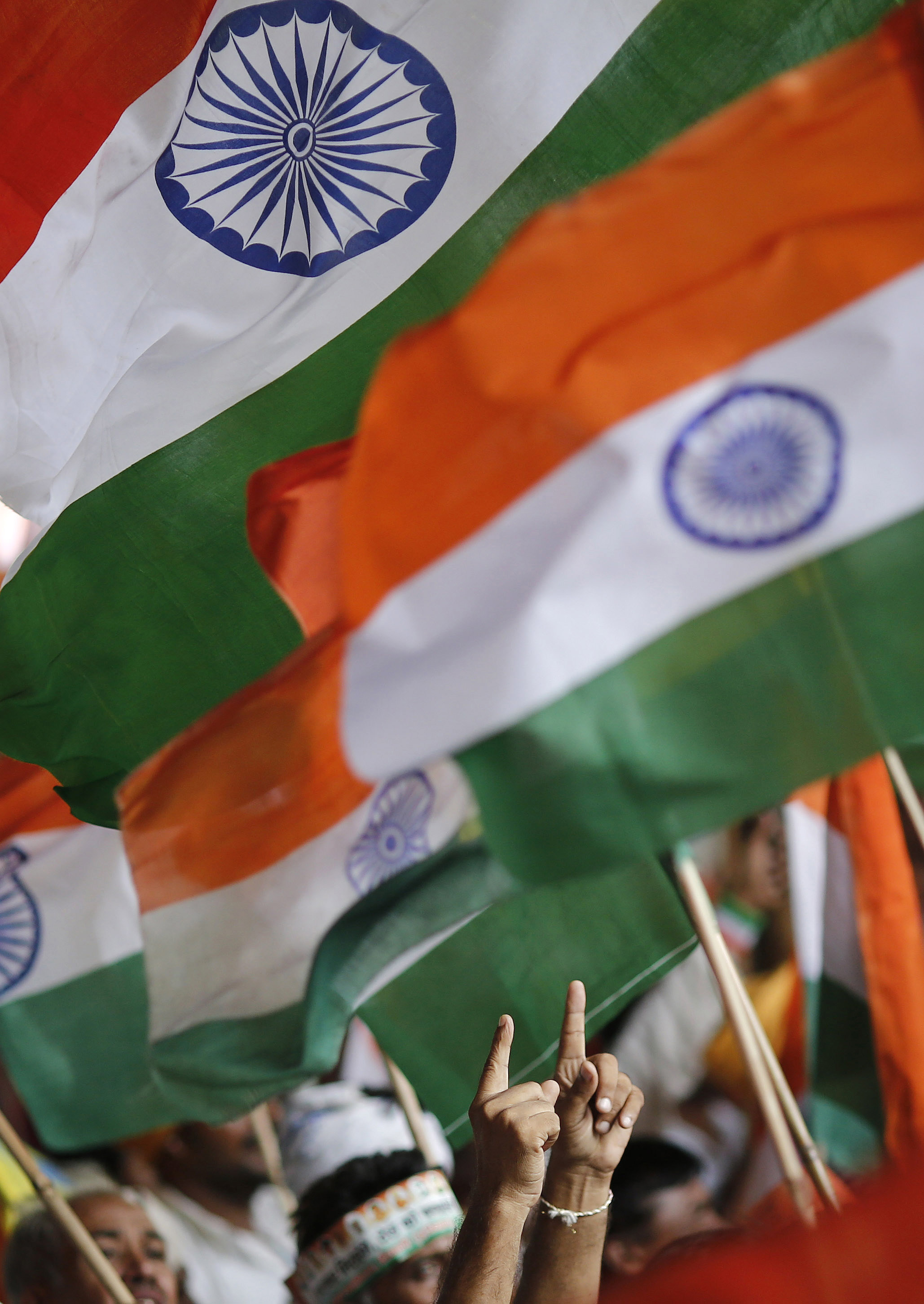 A supporter of Indian yoga guru Ramdev gestures towards Indian national flags while taking part in Ramdev's protest against corruption at the Ramlila grounds in New Delhi