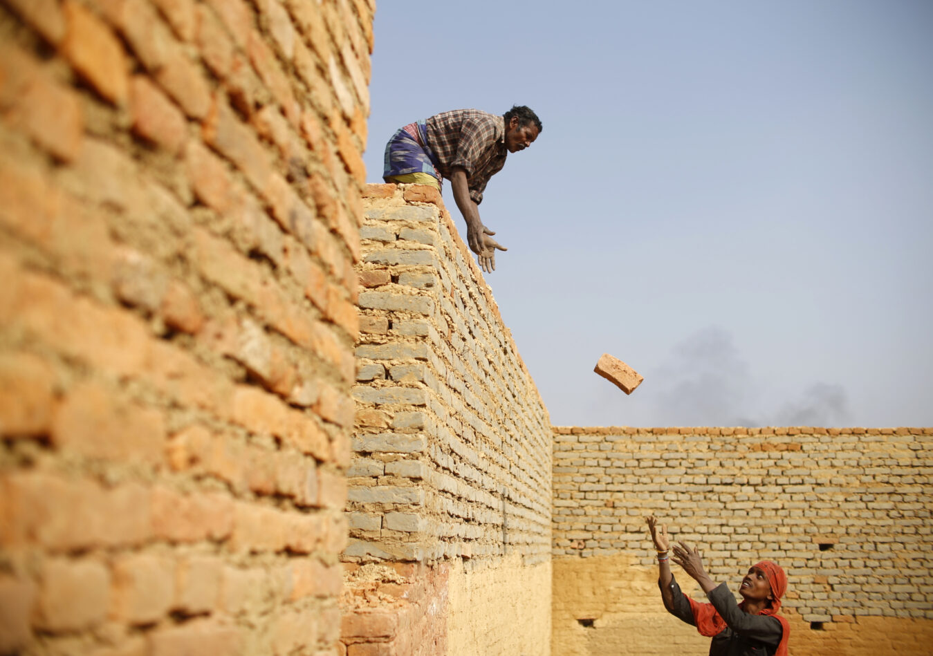 Indian migrant workers pass bricks at a brick factory in Lalitpur