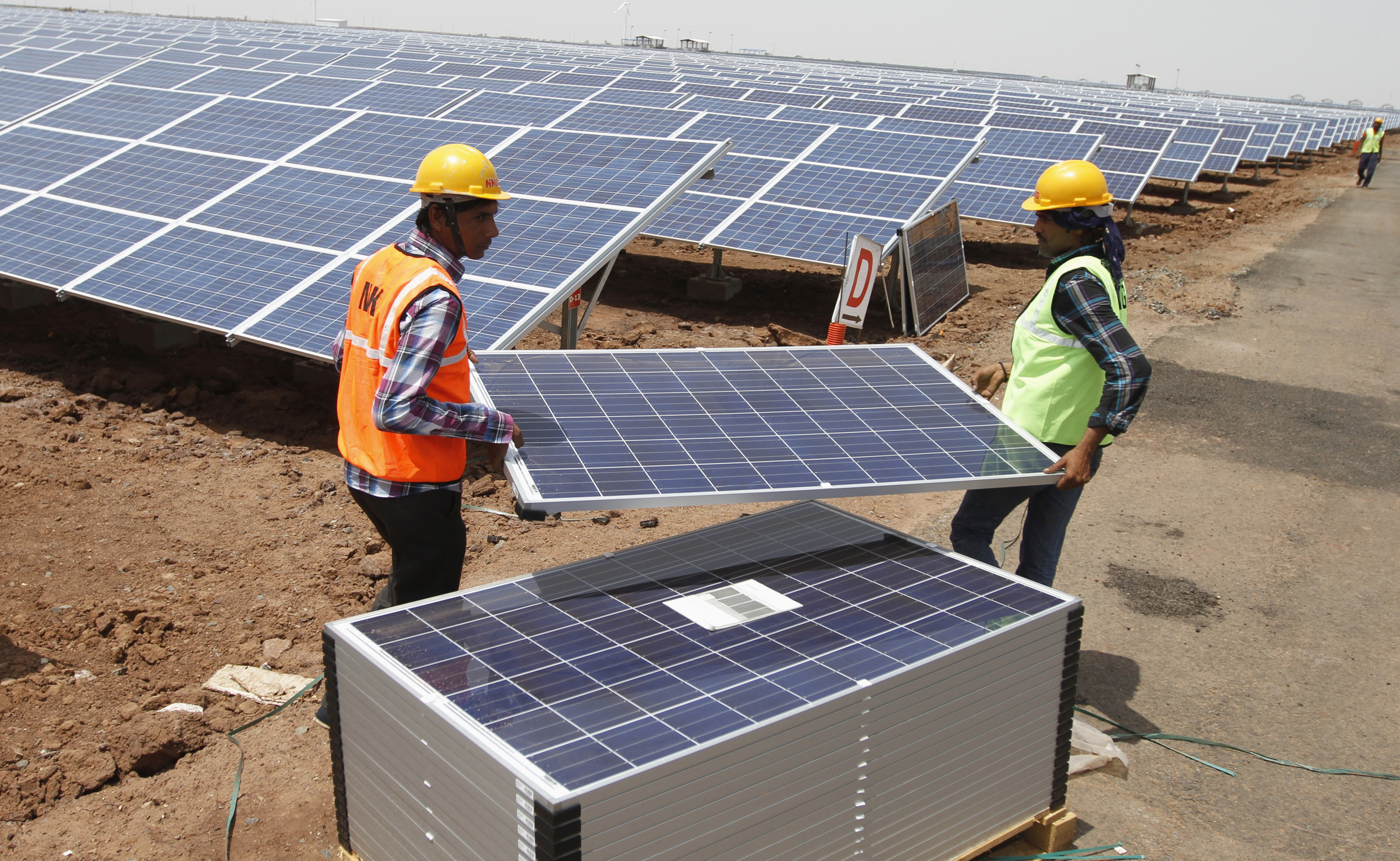 Workers carry photovoltaic solar panels for installation at the Gujarat solar park under construction in Charanka village in Patan district of the western Indian state of Gujarat April 14, 2012. According to officials, the solar park is the largest in India which will generate 210 megawatts and will be operational from April 19, 2012. REUTERS/Amit Dave (INDIA - Tags: BUSINESS ENERGY) - GM1E84E1P7C01